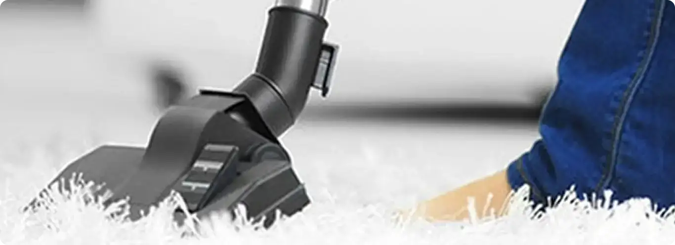 Close-up of a professional vacuuming a white carpet in Allston.