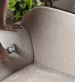Professional upholstery cleaner deep-cleaning a fabric sofa with a handheld extraction tool and hose Cambridge, MA.